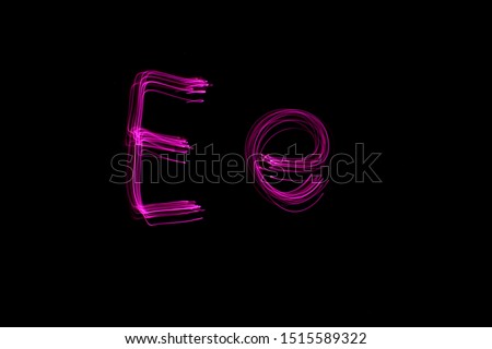 Long exposure photograph of the letter e in upper case and lower case, in pink neon colour in an abstract swirl, parallel lines pattern against a black background. Light painting photography.