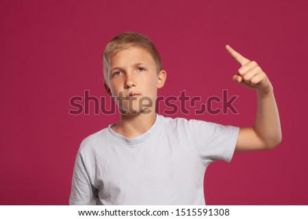 Close-up portrait of a blonde teenage boy in a white t-shirt posing against a pink studio background. Concept of sincere emotions.