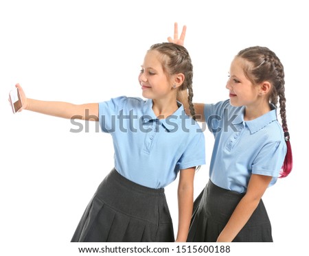 Portrait of twin girls taking selfie on white background