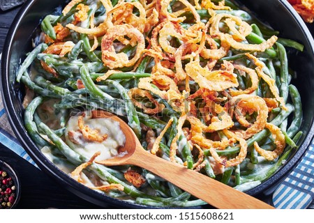 close-up of Green Bean Casserole topped with crispy fried onions in a black dish with spoon,  american cuisine, view from above Royalty-Free Stock Photo #1515608621