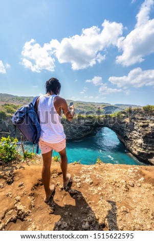 Travel people with backpack and in shorts on the ocean, cliffs and tropical beach background. Angel's Billabong beach, Nusa Penida, Indonesia. 