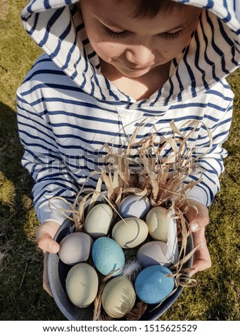 child boy in a striped sweatshirt holds a dish in his hands with easter eggs in a rustic style