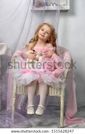 young cute princess in pink sits in a chair with toys