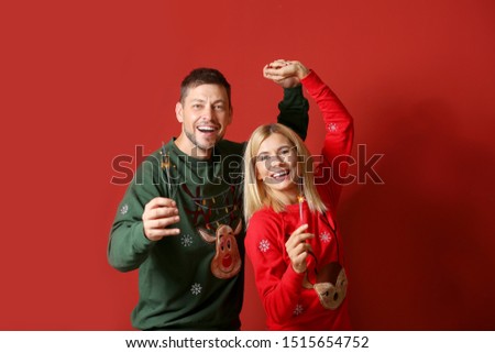 Happy couple with Christmas sparklers on color background