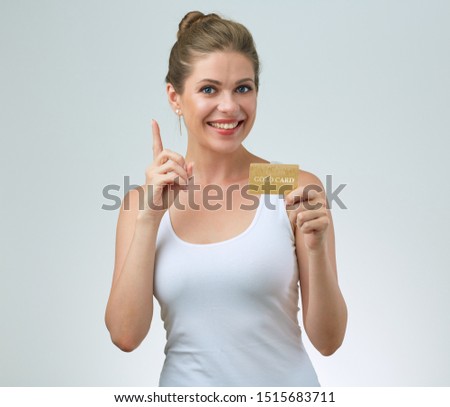 happy woman in white casual vest holding credit card in front of and pointing finger. isolated female portrait.