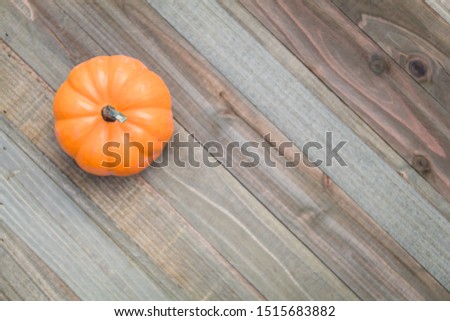 Pumpkin and golden autumn leaves on wooden board flat lay