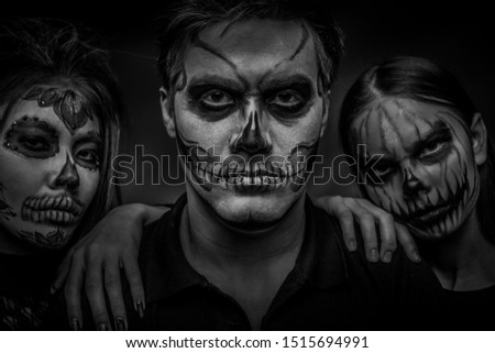 Male and female face art for Halloween. Black and white portrait of a guy and two girls with scary painted faces on a black background. All saints ' night.