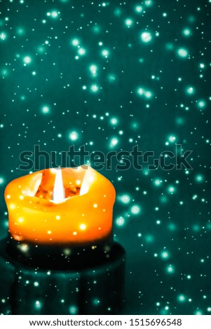 Happy holidays, greeting card and winter season concept - Orange holiday candle on green sparkling snowing background, luxury branding design for Halloween, New Years Eve and Christmas