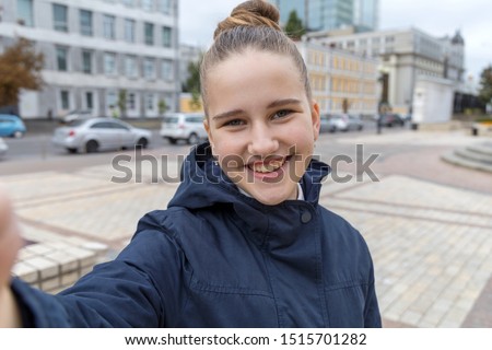 Selfie portrait of a teenage girl on a city background.