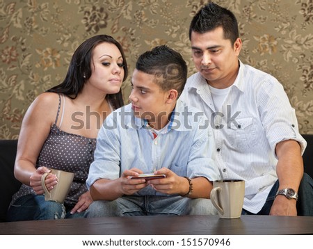 Clever Hispanic teenager watching parents watch his text messaging