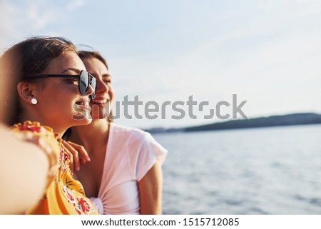 Selfie of two smiling girls outdoors that have a good weekend together at sunny day against the lake.
