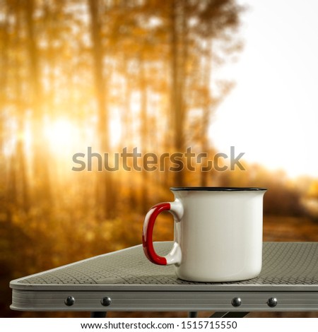 Autumn time and thermos on metal picnic table. Free space for your decoration and fall landscape with sunset time. 