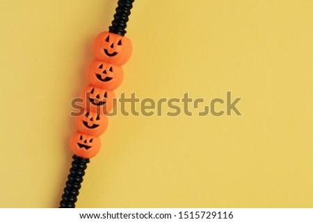 one black decorative cocktail straws with orange happy pumpkin smiley faces on yellow background, Halloween drinks menu design for cocktail party, copy space for text