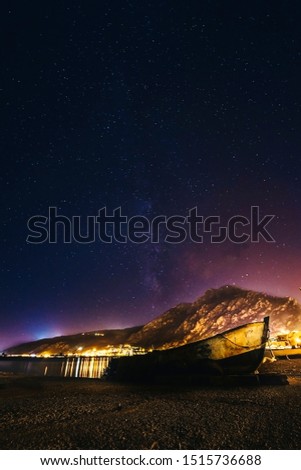 skyline with full of star and a wooden boat under the milky way at night time