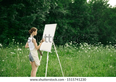 woman easel in nature paints a picture