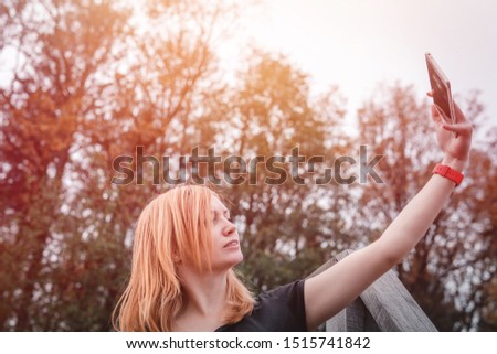 Happy woman smiling using a phone. outdoor hiking adventure. forest background. autumn day. communication, internet network. copy space, taking selfies, taking pictures. Red watch, soft light