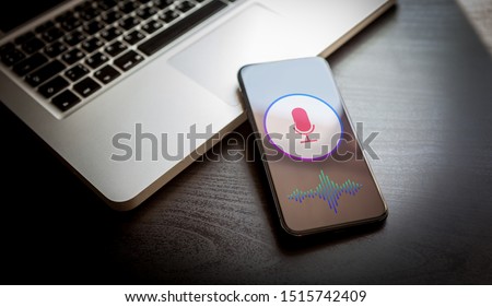 Speech recognition concept - close-up mobile phone with siri microphone icon and wave sound symbol. Personal voice assistant, deep learning application on smartphone screen. Royalty-Free Stock Photo #1515742409