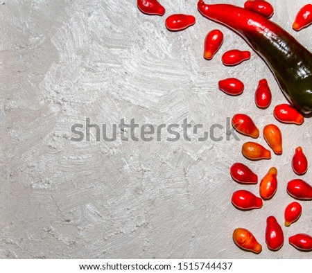 On a white structural background lies red hot pepper with red greasy berries. Picture for design.

