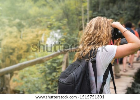 Travel and hobby lifestyle. Active vacations. Woman photographer taking a photo of a beautiful green landscape with a camera.  