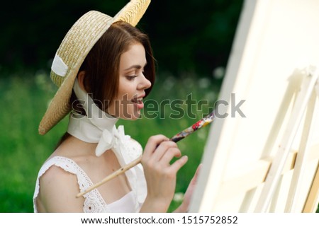 young woman in a straw hat draws with a brush