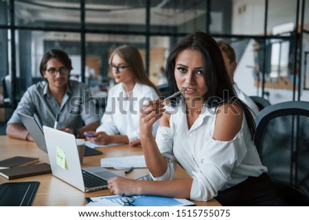 Brunette woman in front of employees. Young business people in formal clothes working in the office.