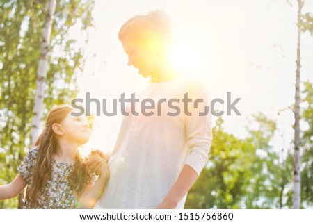 Mother and daughter walking in farm with yellow lens flare in background