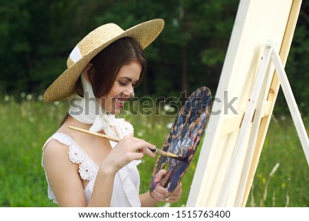 beautiful woman paints an easel young outdoors
