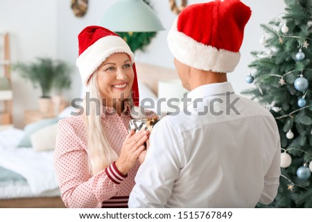 Mature husband giving his wife Christmas present at home
