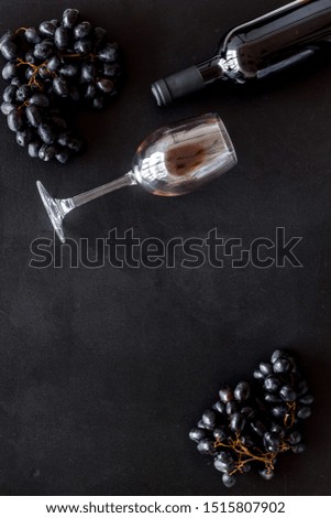 Red wine bottle near wineglass on black background top view copy space