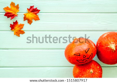 Scary Halloween pumpkin with drawn face on green wooden background top view copy space