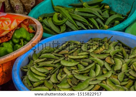 Stock photo of fresh lady finger , green broad  beans and capsicum kept in plastic container or round shape plastic basket for sale in Indian local vegetable market at Kolhapur Maharashtra India.