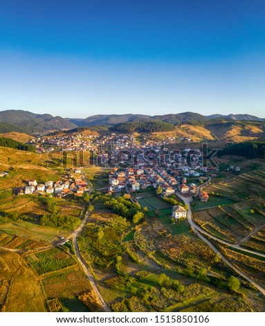 Aerial view of the  village on the background of green hills,fog and the bright rays of the sunrise. Locality Vilagge Zmeitsa, Bulgaria. Drone shot
