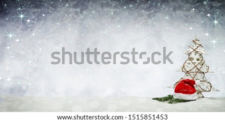 a beautiful christmas picture with a santa claus hat and a little christmas tree and christmas decoration on a grey sky with snow flakes