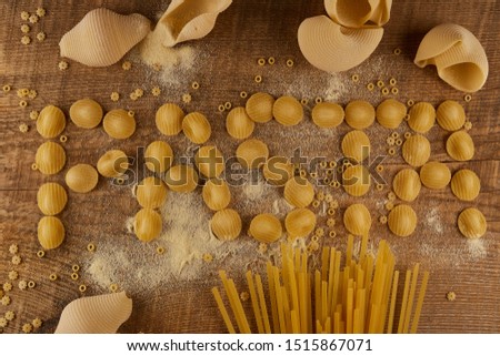Many different pasta on a wooden board. Lettering pasta with different pasta.