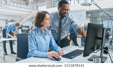 In the Industrial Engineering Facility: Portrait of the Smart and Beautiful Female Engineer Working on Desktop Computer, Her Supervisor Gives Useful Advice about Project Details. Royalty-Free Stock Photo #1515878141