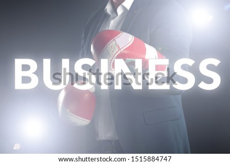 Business man in suit and boxing gloves in isolated flare background with business word on front 