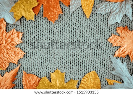 Autumn composition with golden leaves frame on knitted gray background. Fall mockup with gold maple leaves. Flat lay, top view, copy space.