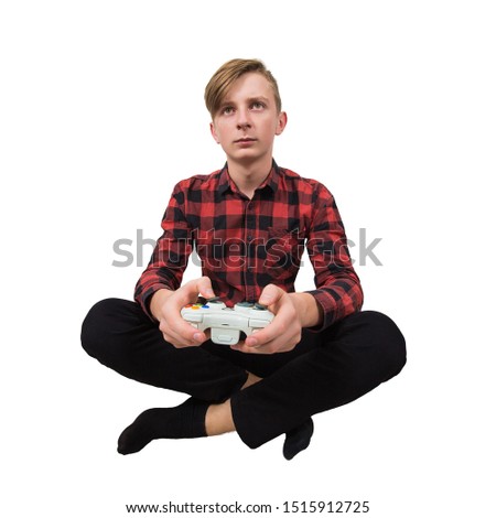 Serious intent teen guy seated on the floor playing video games isolated over white background. Boy stand all ears holding joystick console looking attentive try to win in the virtual world.