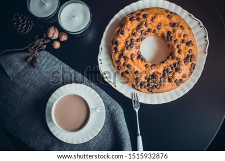 Top view cake, cup of coffee or cocoa, candles, natural cones and nuts decor on the dark table. Cozy atmosphere at home. Breakfast in noir nordic style. Hygge concept. Soft selective focus. Copy space