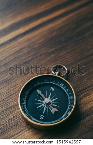 One single gold compass on top of a wooden desk