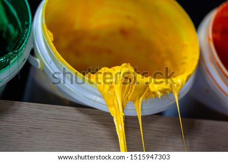 yellow color of ink for print tee shirt. Plastisol ink in white barrel are dripping. Plastisol ink useful for print tee shirt