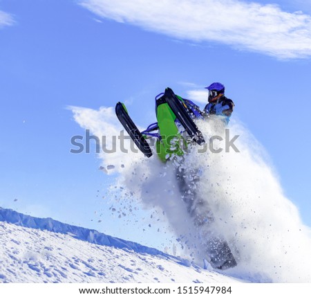 the guy is flying and jumping on a snowmobile on a background of blue sky leaving a trail of splashes of white snow. bright snowmobile and suit without brands. extra high quality Royalty-Free Stock Photo #1515947984
