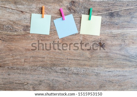 Blank paper stickers on the rope with pins on a wooden background. Free space for text.