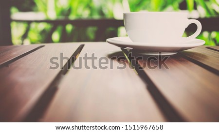 Coffee cup on wood table in garden. - vintage style effect picture