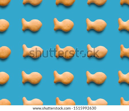 Rounded fresh crispy fish shaped cookies on light blue background. Seamless texture. Top view