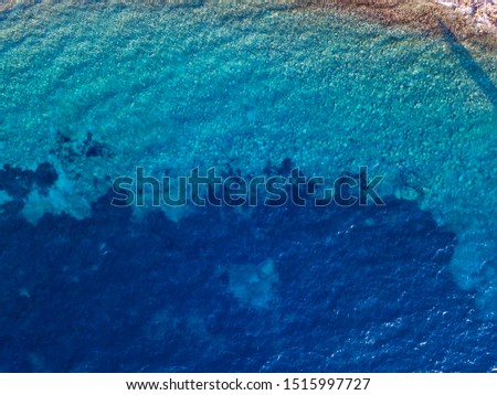 Aerial view of a seabed seen from above, sunset time, Adriatic sea, Montenegro. Swimmers, bathers floating on the water.