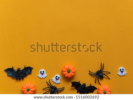 Halloween holiday concept, Pumpkins, black spider, bats and tiny ghost in orange background with copy space for text, Top flat view wallpaper