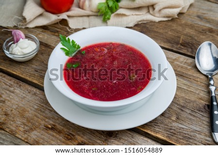 Borscht with sour cream on wooden table