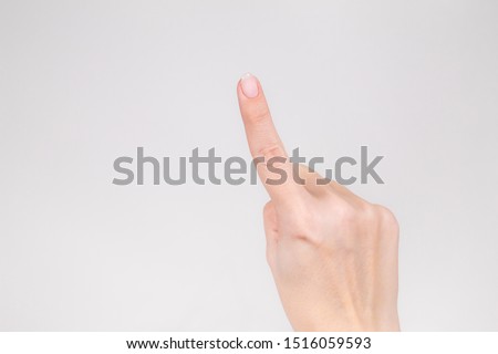 Closeup view of beautiful female hand raising up one index finger. Horizontal color photography.