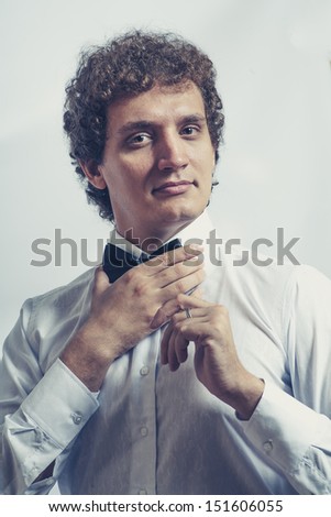 Funny businessman touch bow tie on studio shot. Toned image. Vertical shot